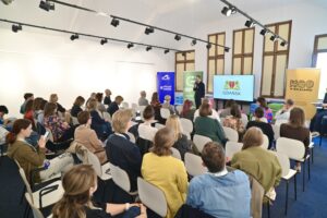 Sala konferencyjna wypełniona uczestnikami Regionalnego Forum Praktyków Partycypacji. Na środku trwa wystąpienie przed ekranem z logo Gdańska.