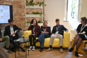 Panel dyskusyjny z udziałem młodych osób siedzących na kanapach i rozmawiających o partycypacji młodzieży.