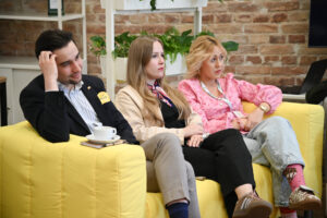 Panel dyskusyjny z udziałem młodych osób siedzących na kanapach i rozmawiających o partycypacji młodzieży.
