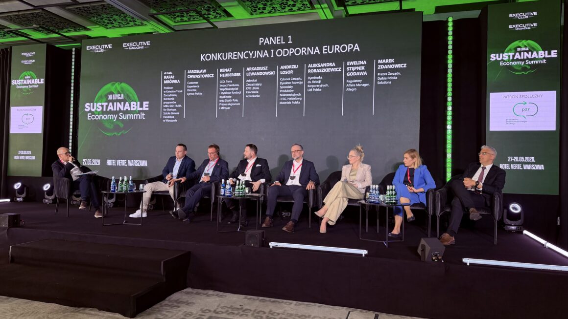 Panel dyskusyjny podczas Sustainable Economy Summit w Warszawie. Na scenie siedzi moderator oraz siedmioro panelistów rozmawiających o konkurencyjności i odporności Europy. W tle widoczny jest duży ekran z tytułem panelu „Konkurencyjna i odporna Europa”, nazwiskami prelegentów oraz logotypami wydarzenia i patrona społecznego Pracowni Zrównoważonego Rozwoju.